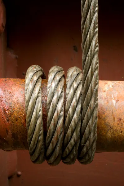 El cable de acero es una herramienta multifuncional que sirve para la carga y descarga de materiales de mucho volumen o peso. Cable de acero de gran aguante sujetando y levantando un tubo de acero de mucho peso.