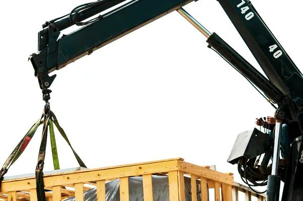Grua con brazo de acero cargando una caja de madera de gran tamaño de como funciona una eslinga.