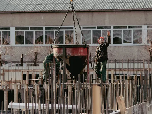 Trabajadores del sector de construcción utilizando los tipos de eslingas de cadena para cargar toneladas de cemento.